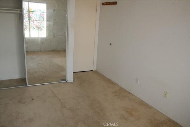 unfurnished bedroom featuring light colored carpet and a closet