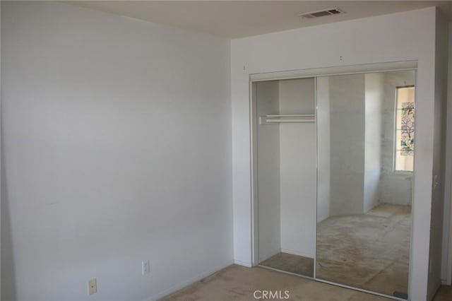 unfurnished bedroom featuring light carpet and a closet