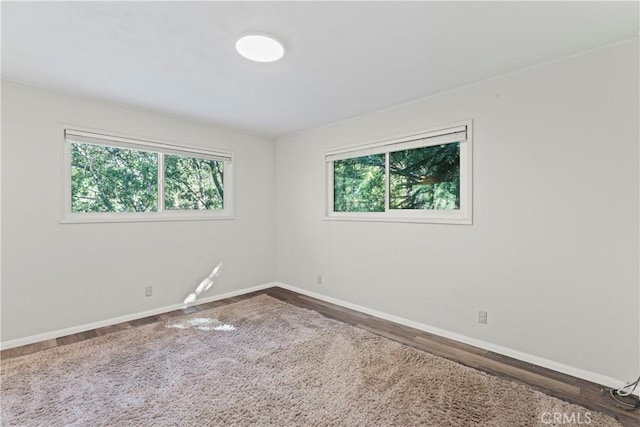 empty room with plenty of natural light, baseboards, and dark wood finished floors