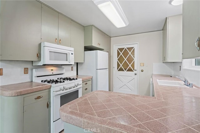 kitchen with white appliances, light countertops, a sink, and a peninsula