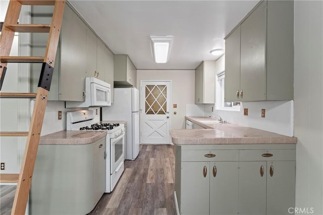 kitchen with a sink, light countertops, white appliances, and wood finished floors