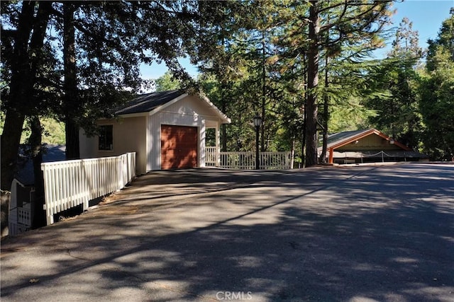 view of front of home featuring driveway, an attached garage, and fence