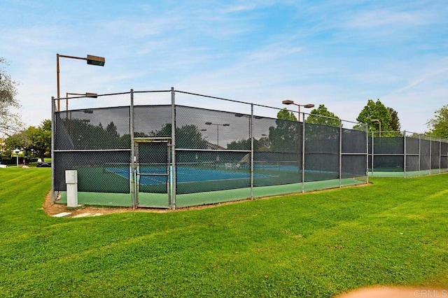 view of tennis court with a yard