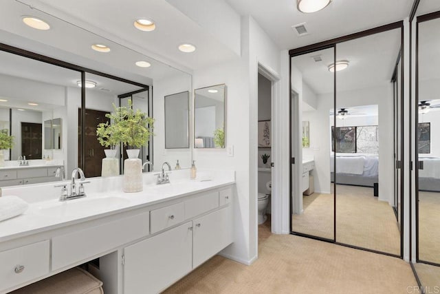 bathroom featuring toilet, vanity, and ceiling fan