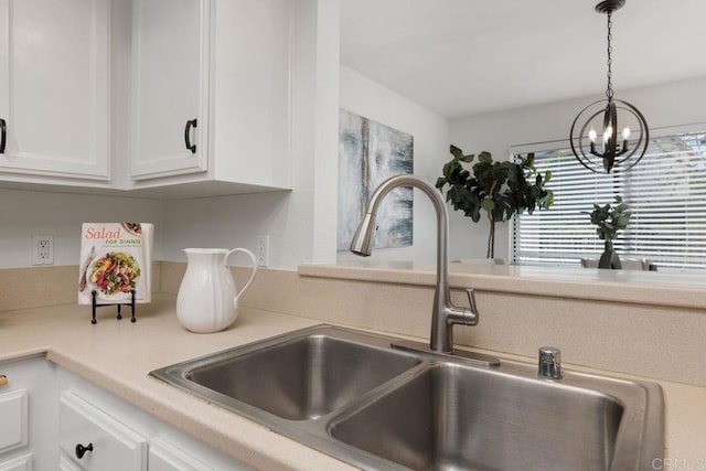 room details featuring white cabinets, sink, and decorative light fixtures