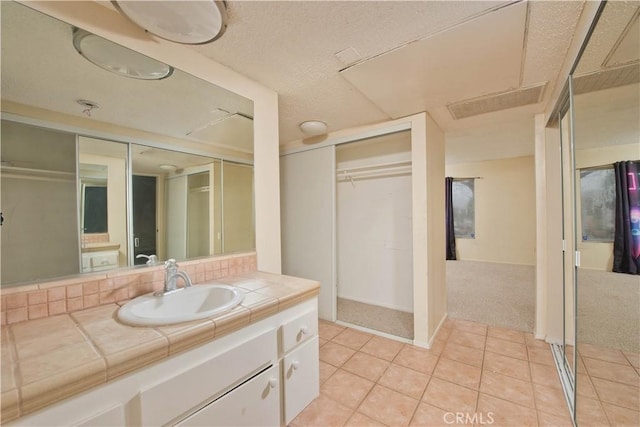 23515 Lyons Ave Unit 228, Valencia, CA 91355 - bathroom with vanity, tile patterned flooring, a walk in closet, and a textured ceiling
