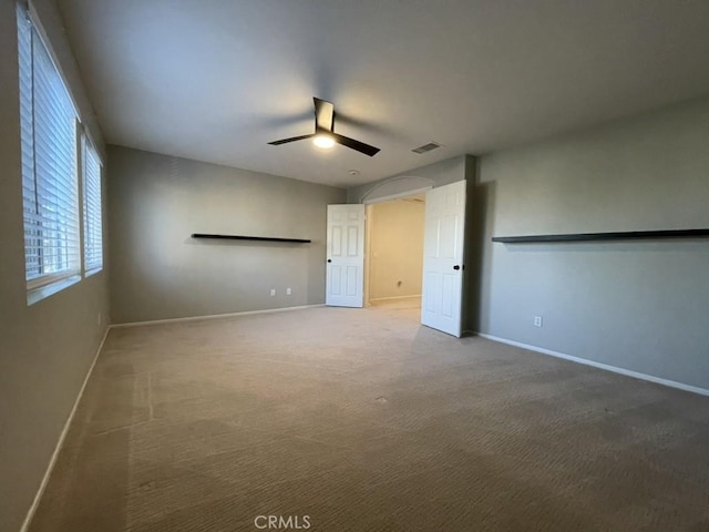 spare room featuring a ceiling fan, visible vents, carpet floors, and baseboards