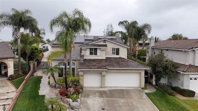 traditional home with a garage, concrete driveway, fence, roof mounted solar panels, and stucco siding