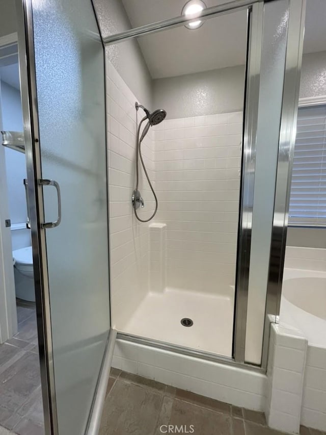 bathroom with a stall shower, tile patterned floors, toilet, and a bath