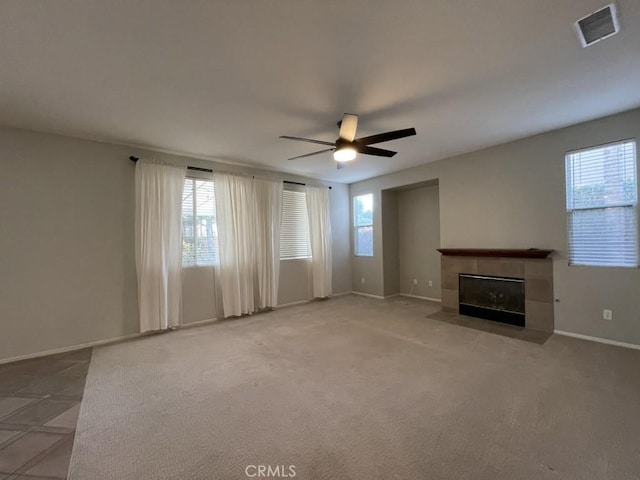 unfurnished living room with plenty of natural light, ceiling fan, a fireplace, and visible vents