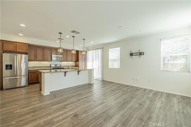 22059 Barrington Way, Saugus, CA 91350 - kitchen with stainless steel appliances, recessed lighting, a kitchen island with sink, a kitchen breakfast bar, and wood finished floors
