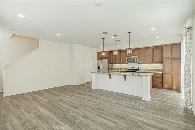 22059 Barrington Way, Saugus, CA 91350 - kitchen with stainless steel appliances, light wood finished floors, an island with sink, a kitchen bar, and recessed lighting
