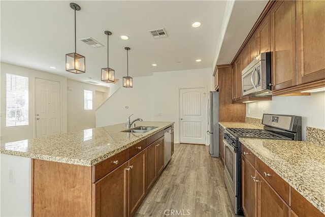 22059 Barrington Way, Saugus, CA 91350 - kitchen featuring stainless steel appliances, a sink, light wood finished floors, a center island with sink, and light stone countertops