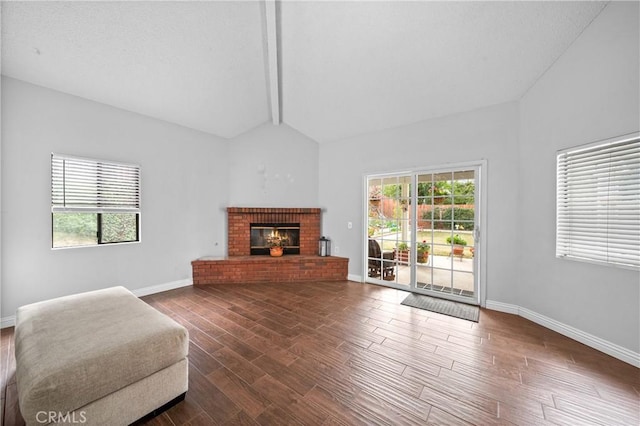 living room with a brick fireplace, vaulted ceiling with beams, a wealth of natural light, and dark hardwood / wood-style floors