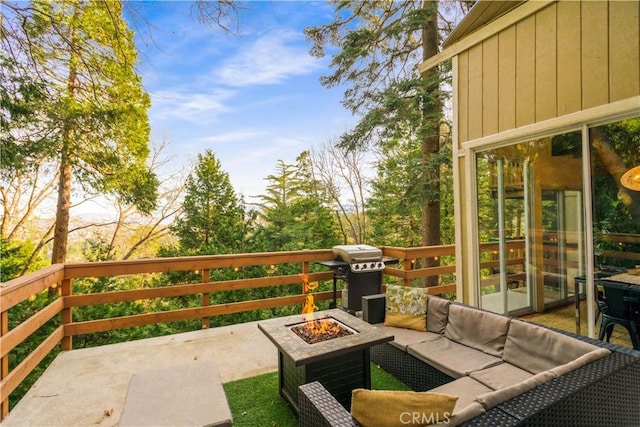 wooden terrace with area for grilling and an outdoor living space with a fire pit