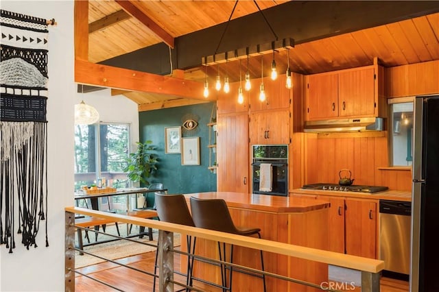 579 E Victoria Ct, Lake Arrowhead, CA 92352 - kitchen with wood walls, wooden ceiling, under cabinet range hood, and appliances with stainless steel finishes