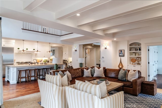 living room with beamed ceiling, sink, hardwood / wood-style floors, and built in features