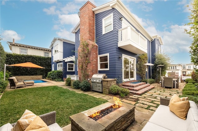 rear view of property with a patio, an outdoor kitchen, an outdoor living space with a fire pit, and a lawn