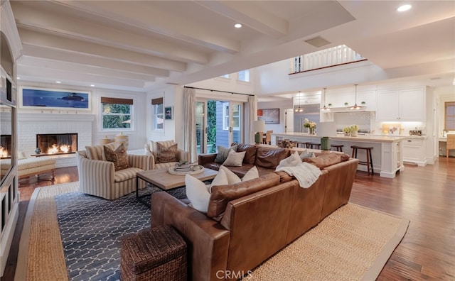 living room featuring light hardwood / wood-style flooring, a fireplace, and beamed ceiling