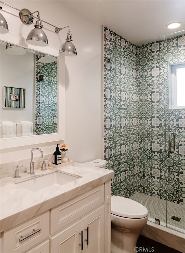 bathroom with vanity, toilet, and a shower with shower door