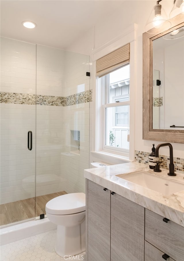 bathroom featuring vanity, an enclosed shower, backsplash, and toilet