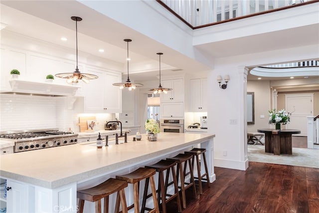 kitchen featuring white cabinetry, hanging light fixtures, stainless steel appliances, and a large island with sink