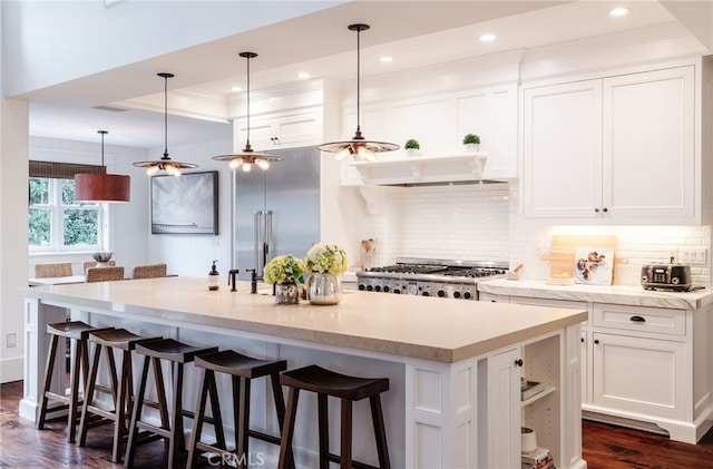 kitchen with pendant lighting, white cabinets, a kitchen bar, and a large island with sink