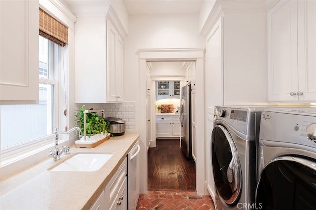 clothes washing area with cabinets, washing machine and clothes dryer, and sink