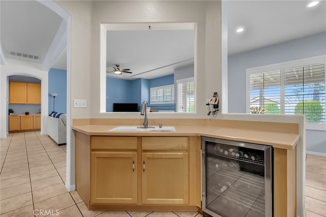 kitchen with sink, light tile patterned floors, wine cooler, kitchen peninsula, and light brown cabinets