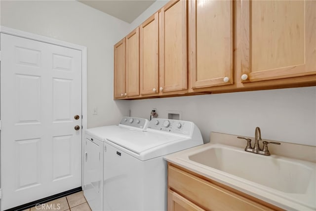 laundry room featuring light tile patterned flooring, cabinets, sink, and washer and dryer