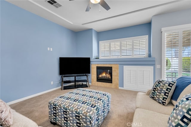 carpeted living room featuring a tiled fireplace and ceiling fan