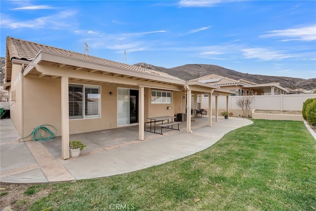 rear view of house with a patio, a mountain view, and a yard