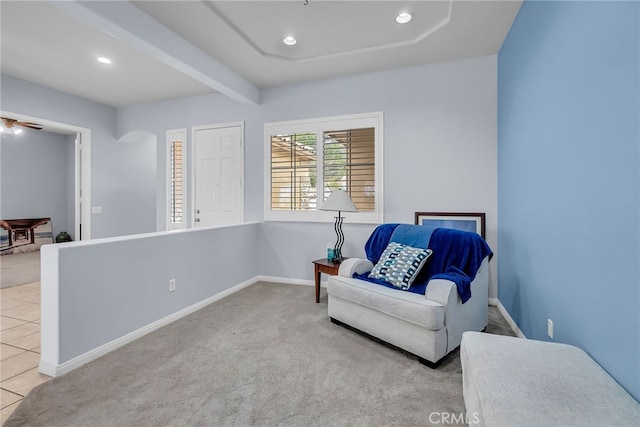 sitting room featuring light colored carpet and beamed ceiling