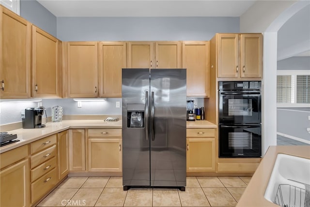 kitchen with black double oven, sink, light brown cabinetry, and stainless steel fridge with ice dispenser