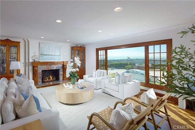 living room with ornamental molding, a premium fireplace, and light hardwood / wood-style floors