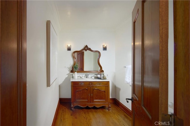 bathroom featuring vanity, hardwood / wood-style floors, and ornamental molding