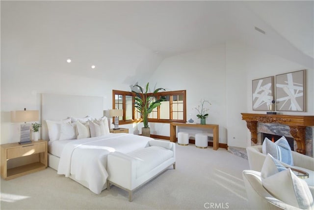 carpeted bedroom with a fireplace and vaulted ceiling