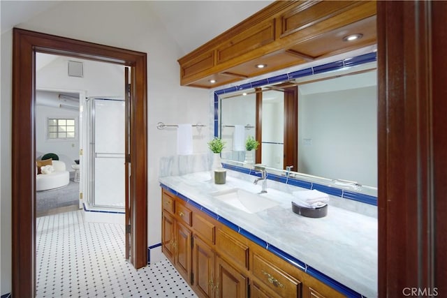 bathroom with a shower with door, vanity, and vaulted ceiling