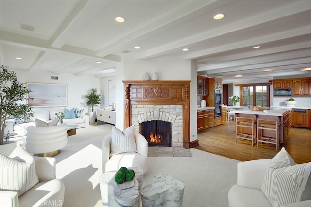 living room with light hardwood / wood-style flooring, a fireplace, and beamed ceiling