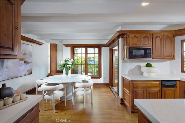 kitchen with black microwave, beam ceiling, and light hardwood / wood-style floors