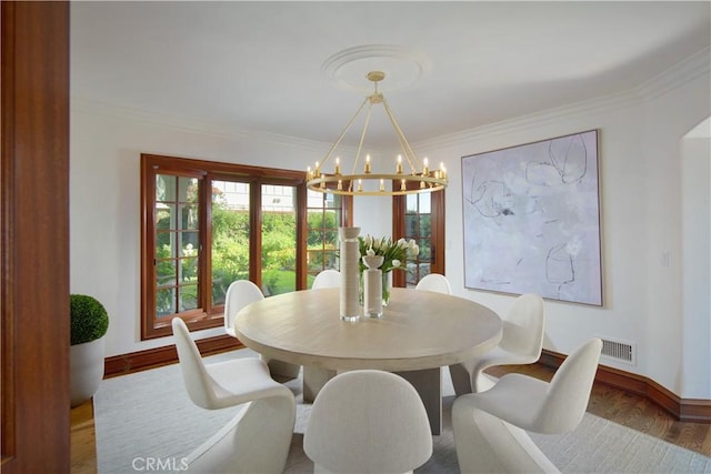 dining space with crown molding, hardwood / wood-style floors, and a notable chandelier