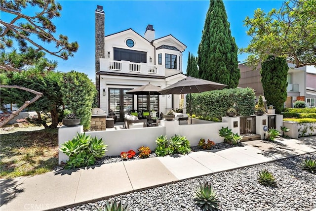 back of house with a fenced front yard, french doors, and a balcony