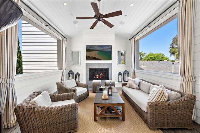 living room featuring lofted ceiling, ceiling fan, a warm lit fireplace, recessed lighting, and wood finished floors