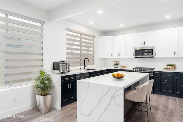 kitchen with white cabinetry, appliances with stainless steel finishes, a kitchen island, and a wealth of natural light