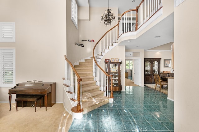 carpeted entryway with a high ceiling, stairway, and baseboards