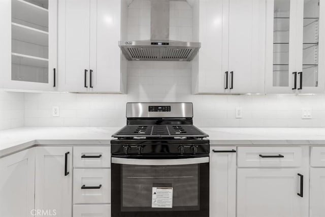 kitchen with white cabinetry, wall chimney exhaust hood, light stone countertops, and stainless steel gas range oven