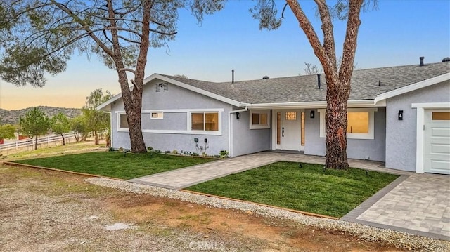 single story home featuring a garage and a yard