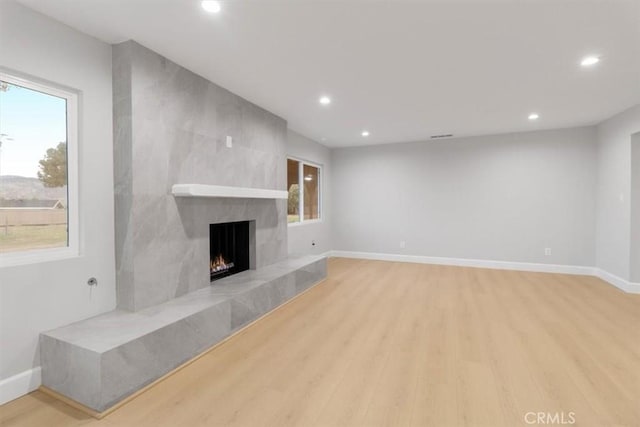 unfurnished living room featuring a fireplace and light hardwood / wood-style flooring