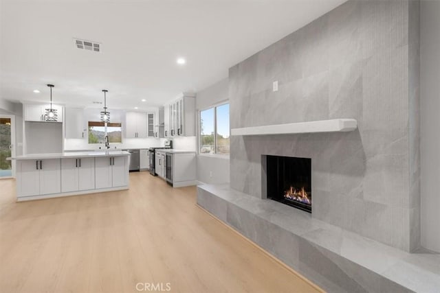 kitchen featuring sink, white cabinets, hanging light fixtures, light hardwood / wood-style floors, and stainless steel appliances