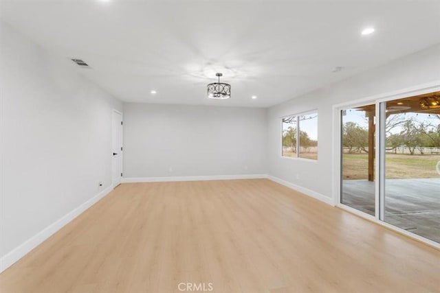 empty room with an inviting chandelier and light hardwood / wood-style flooring